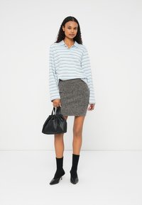 Vaaleansininen raidallinen pitkähihaisuus, harmaa teksturoitu neulottu hame, mustat korkokengät ja musta rypistetty käsilaukku.