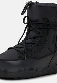 Černá voděodolná sněhová bota s polstrovaným horním dílem, zaoblenou špičkou, nastavitelným zavazováním na tkaničky a texturovanou gumovou podrážkou pro lepší přilnavost.