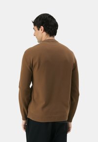 Maglione marrone a maglia con colletto e polsini a coste. Morbida consistenza, vestibilità rilassata e design senza cuciture sul retro. Adatto per un abbigliamento casual.