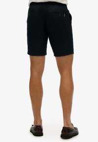 Marinefarbene Shorts aus Baumwolle, mit einem verstellbaren Kordelzugbund, zwei seitlichen Taschen und zwei aufknopfbaren Gesäßtaschen, mit einer glatten Textur.
