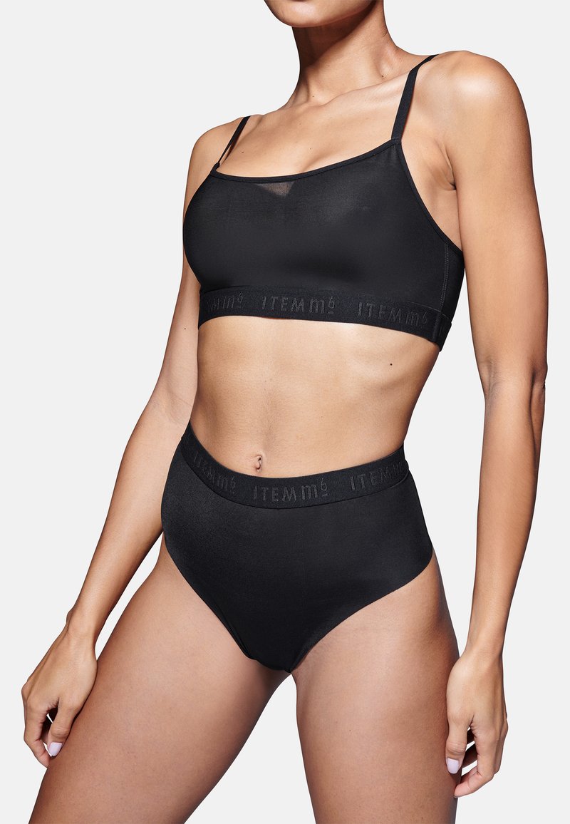 Set di bralette nera e mutandine a vita alta realizzato in tessuto morbido. Presenta spalline sottili e una fascia con dettagli in rilievo del logo del marchio.