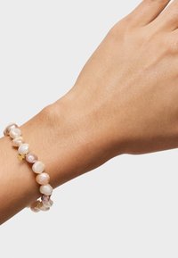 Bransoletka z pereł, zawierająca mix różowych i białych nieregularnych pereł, elastyczny design oraz mały złoty charms.
