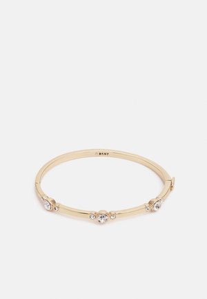 Armband in goudkleur met drie sets heldere ronde kristallen, gelijkmatig verdeeld over de band, binnen gegraveerd met "DKNY".