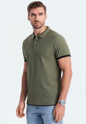 Polo de color verde oliva oscuro hecho de algodón, con un cuello y tres botones, acentos negros en las mangas y un dobladillo recto.
