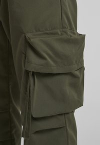 Olive green cargo pants featuring a side pocket, smooth fabric texture, and a relaxed fit, ideal for practical use.