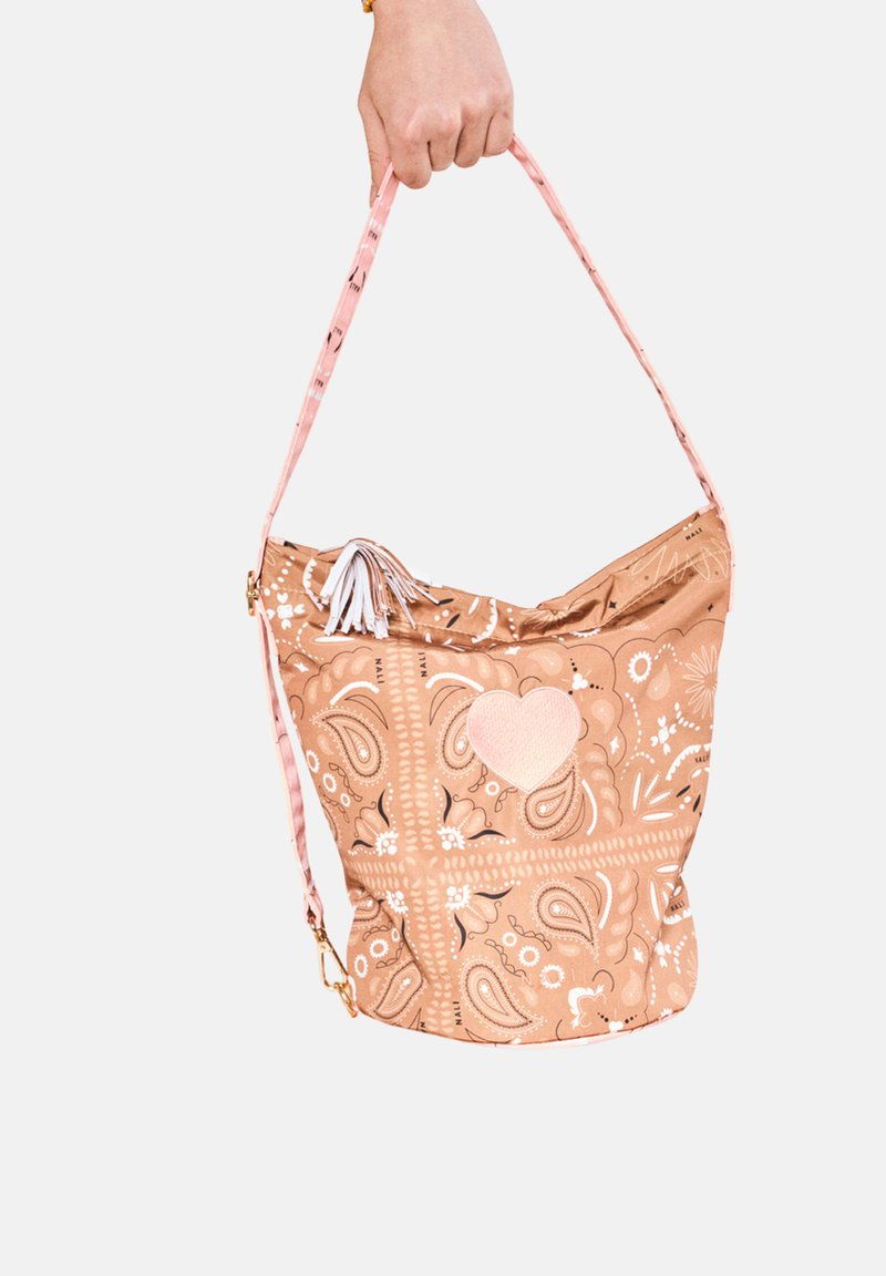 La borsa a secchiello a motivo marrone chiaro presenta una tracolla rosa, un dettaglio a forma di cuore e delle frange. Il design include motivi floreali e paisley.