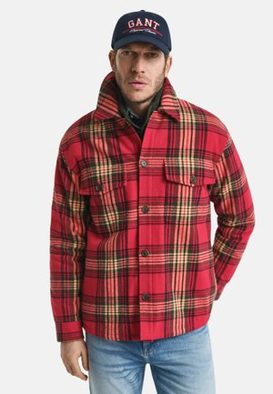 Rot-schwarz kariertes Flanellhemd mit zwei Brusttaschen und einem Kragen, kombiniert mit blauen Denim-Jeans.