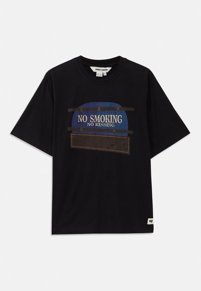 Camiseta de algodón negra con mangas cortas, que presenta un diseño gráfico que incluye el texto "SIN FUMAR" y "SIN BESOS" en acentos azules y blancos.