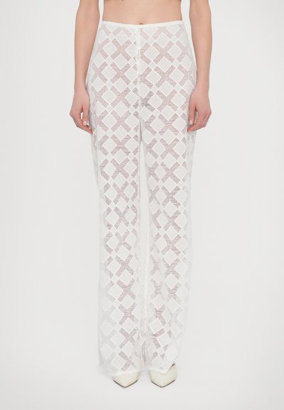 Pantalons évasés blancs et texturés avec un motif géométrique en losanges. Le tissu est léger et semi-transparent avec une finition douce.
