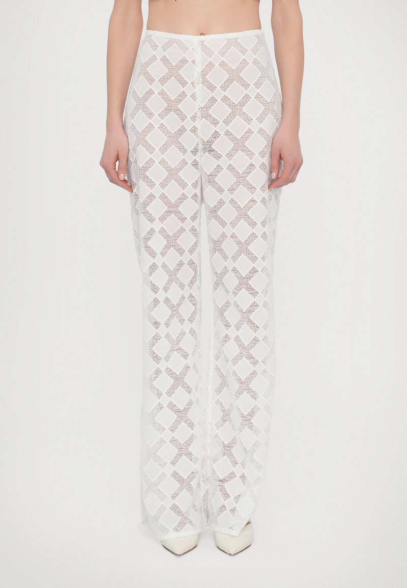 Witte, gestructureerde, wijde broek met een geometrisch ruitpatroon. De stof is doorzichtig en semi-transparant met een zachte afwerking.