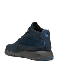 Zapatilla alta de color navy que combina cuero liso y malla texturada. Tiene un talón redondeado, suela acolchada y acentos en azul que contrastan.