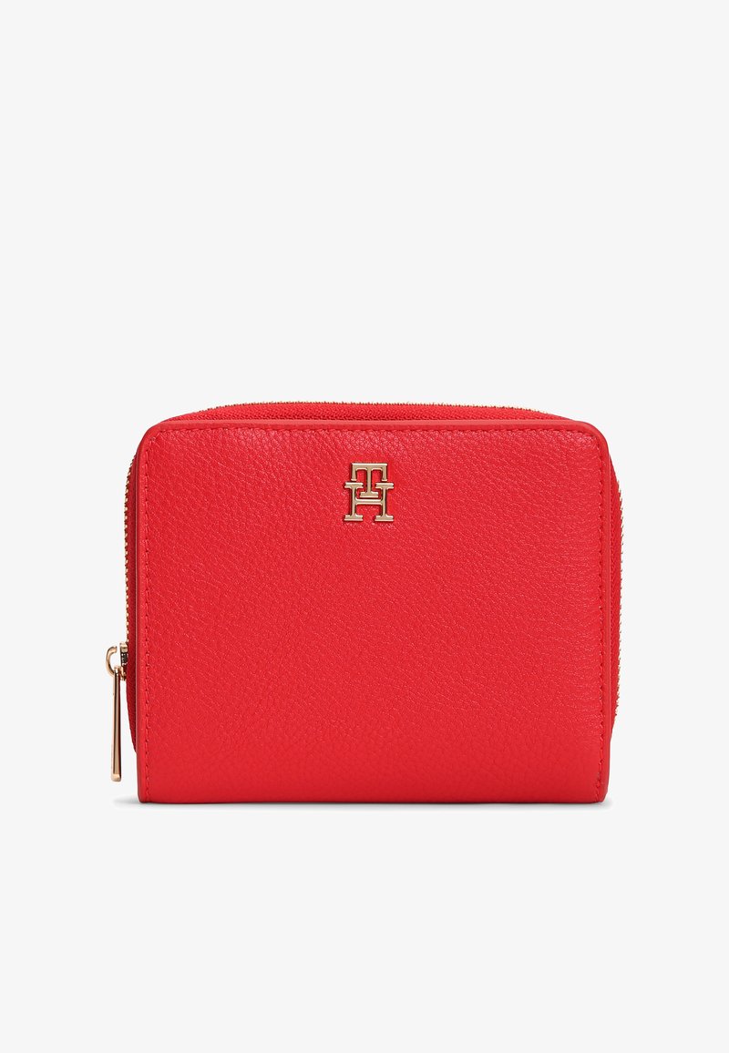 Κόκκινο δερμάτινο πορτοφόλι με ανάγλυφη υφή, με χρυσό λογότυπο στη μπροστινή πλευρά και φερμουάρ κλεισίματος. Компакτ ορθογώνιο σχήμα.