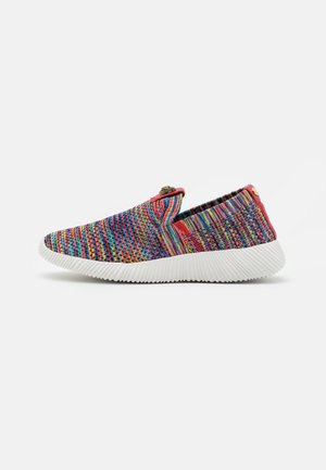 Deportiva tipo slip-on de punto colorida con suela blanca texturizada y ribete rojo, mostrada de lado sobre un fondo liso.