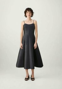 Čierne saténové midi šaty s tenkými ramienkami, v áčkovom strihu, hladkou textúrou, mierne rozšíreným lemom a jednoduchým, elegantným dizajnom.