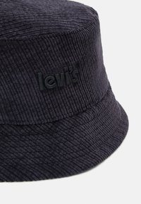 Kapelusz typu bucket w ciemnoniebieskim korduroju, z żebrową teksturą i wytłoczonym czarnym logo "Levi's" z przodu.