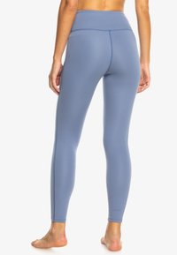 Leggings de yoga taille haute en bleu clair, fabriqués dans un tissu extensible et lisse. Présentent un design épuré avec des coutures latérales et sans motifs visibles.