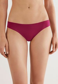 Bikini broekje in diep bordeauxrood. Bevat een gladde, elastische stof met een eenvoudig, laag uitgesneden ontwerp en minimalistische snit.