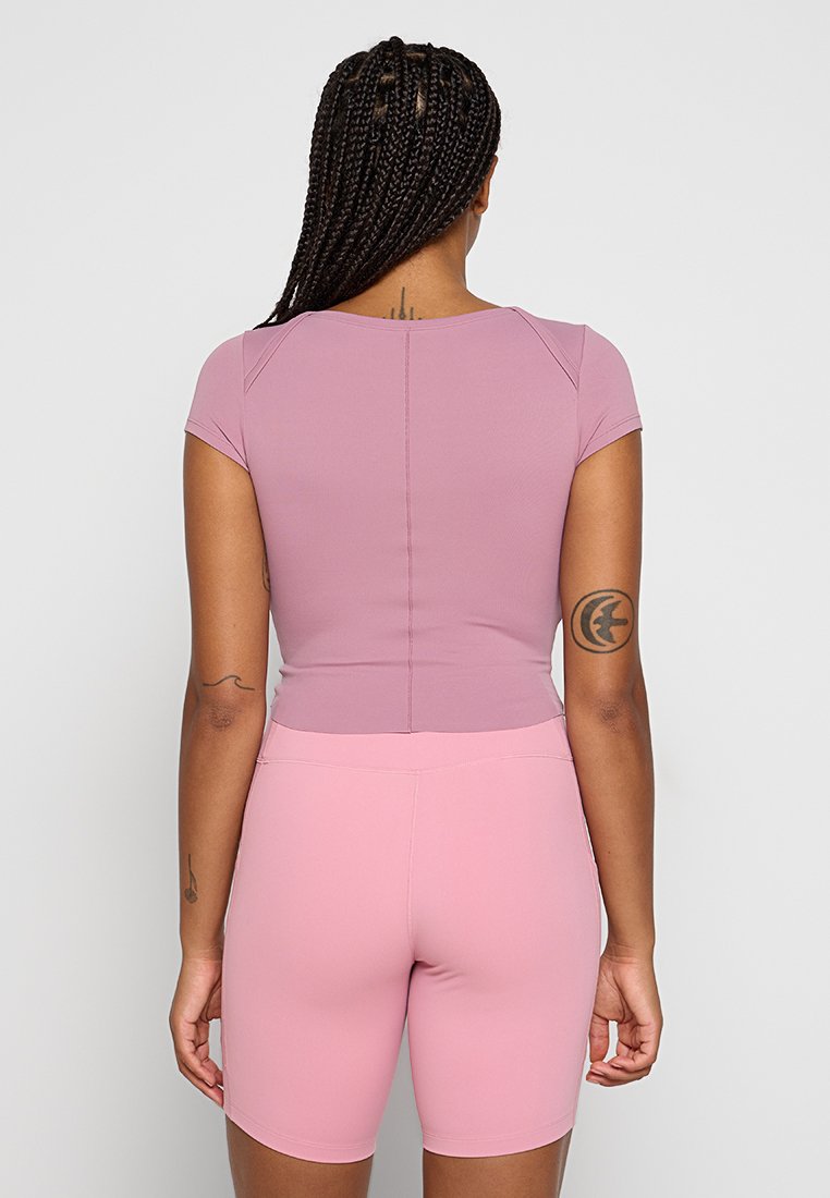 Top fitted a maniche corte e pantaloni abbinati in rosa chiaro. Tessuto morbido e elasticizzato con un design pulito e senza motivi o dettagli visibili.