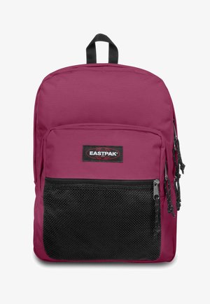 Sac à dos en polyester bordeaux avec une poche frontale en maille noire, fermeture zippée et poignée de transport sur le dessus. Présente un patch logo Eastpak.