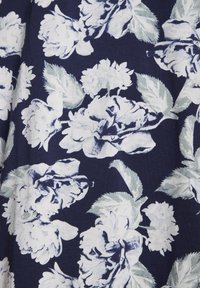 Tessuto blu navy con un motivo floreale caratterizzato da grandi rose bianche e azzurre chiare e foglie verdi, creando un aspetto strutturato e stratificato.