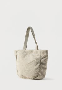 Τσάντα ώμου φτιαγμένη από κρεμ χρώματος ψεύτικη γούνα με απαλή υφή, που διαθέτει δύο υφασμάτινους ιμάντες και έναν απλό, αδιάκοπο σχεδιασμό.