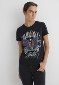 Black cotton t-shirt featuring a large butterfly graphic in purple and orange, surrounded by daisies and text. Short sleeves and a crew neck.