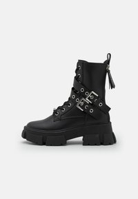 Botines de cuero negro con suelas gruesas, con cordones en la parte delantera, acentos de hardware plateado y cremallera lateral para facilitar su uso.