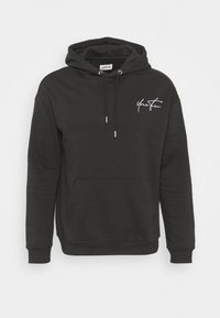 Sudadera negra de tela suave, con un bolsillo tipo canguro en la parte frontal, capucha con cordón y texto blanco "Tu Turno" en el pecho.