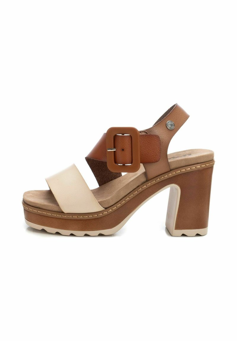 Sandalia de plataforma elevada con una combinación de colores en tonos marrón y beige, que presenta correas anchas, una hebilla cuadrada y un tacón grueso con suela texturizada.