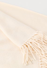 Κασκόλ από μαλλί σε κρεμ χρώμα με απαλό υφή, με φουντωτά άκρα και απλό, μινιμαλιστικό σχέδιο.