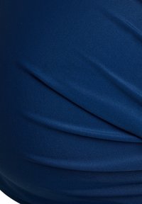 Tessuto blu navy con texture e morbide pieghe, che creano profondità e movimento. Superficie liscia con una leggera lucentezza.