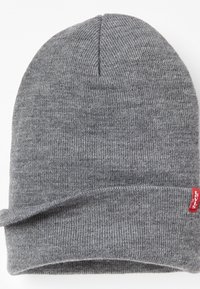 Grijze gebreide muts met een zachte textuur, voorzien van een omgeslagen boord en een klein rood Levi's-label aan de zijkant.