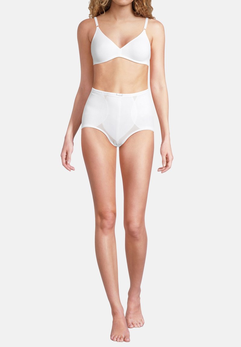 Femme portant un slip gainant taille haute blanc et un soutien-gorge blanc à bonnets souples, debout devant un fond clair uni.