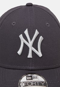 Casquette de baseball gris foncé avec un logo "NY" blanc en relief brodé sur le devant. Comprend une sangle ajustable en tissu et des détails en œillets.