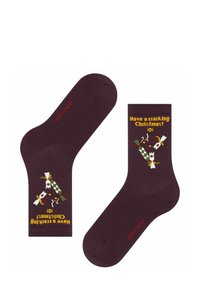 Burgunderfarbene Socken mit festlichem Muster, das Knallbonbons und den Text "Frohe Weihnachten!" in Gelb zeigt. Aus gestricktem Baumwollmischmaterial.