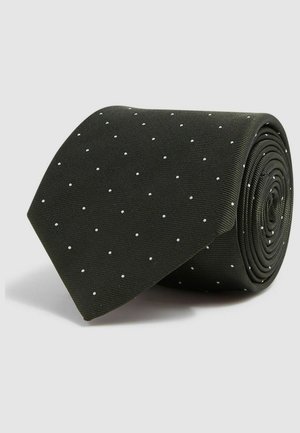 Sorte slips med en struktureret overflade, prydet med små hvide prikker, rullet op i en cirkulær form til opbevaring eller præsentation.