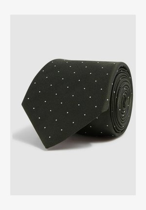 Sorte slips med en struktureret overflade, prydet med små hvide prikker, rullet op i en cirkulær form til opbevaring eller præsentation.