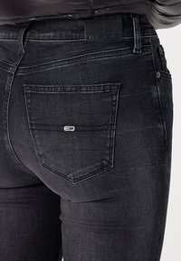 Jeans de mezclilla negra con un diseño ajustado, que cuentan con un bolsillo trasero con un logotipo de color y una textura suave. Costuras definidas y una cintura regular.