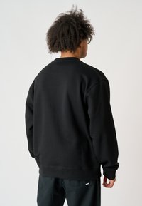 Schwarzer, übergroßer Sweatshirt mit rundem Ausschnitt und langen Ärmeln. Weiches Material, gerippte Bündchen und Saum, minimalistisches Design.