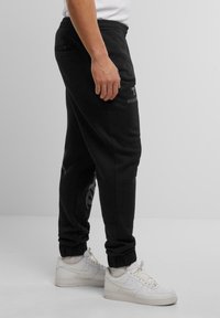 Sorte sweatpants med en afslappet pasform, der har en elastisk talje, ribbede kanter og diskrete logo-accenter på stoffet.