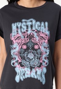 T-shirt en coton noir avec un design graphique coloré en rose et bleu, comportant les mots "RÊVES MYSTIQUES" et des accents floraux.
