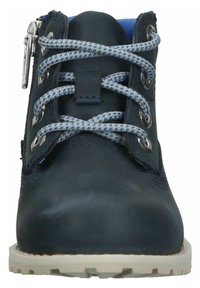 Bota azul oscura con parte superior de cuero texturizado, forro azul, cordones con un patrón gris y azul, herrajes metálicos plateados y una suela de color claro.