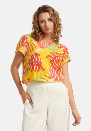 Kurzärmlige, lebhaft gelbe Bluse mit pinkem, orangefarbenem und grünem Blumenmuster; V-Ausschnitt-Design; leichtes Material; lässige Passform.