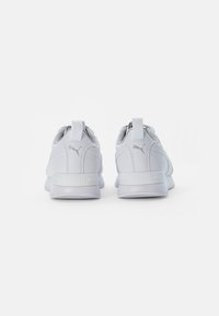 White sneakers with a textured upper, rounded toe, and padded collar. Features a pull tab and embossed logo on the heel. Rubber outsole.