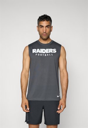 Siva majica bez rukava s natpisom "RAIDERS Nogomet" u bijelom tekstu. Izrađena od glatkog materijala. Uparen s tamnim kratkim hlačama koje imaju natpis "RAIDERS" sa strane.