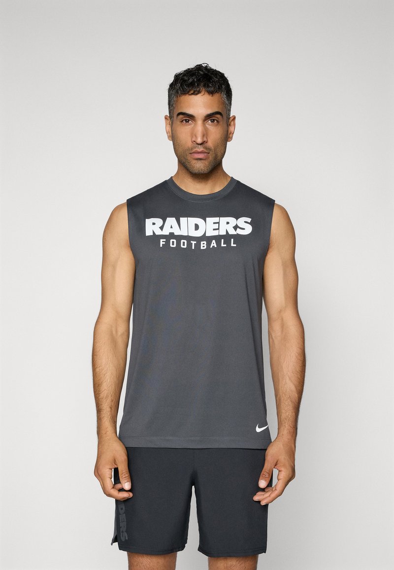 Siva brezrokavnik s tekstom "RAIDERS Football" v belem. Narejen iz gladkega materiala. V par z temnimi hlačami, na katerih je ob strani napis "RAIDERS".