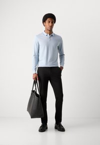 Polo bleu clair à manches longues, pantalon noir, sac fourre-tout en cuir noir et chaussures chunky. Design simple avec un col classique et une coupe décontractée.