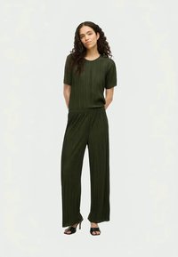 Green pleated co-ord set featuring a short-sleeve top and wide-leg trousers. Smooth texture with an elastic waistband. Simple, modern design.
