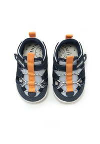 Zapatos infantiles de color azul marino con acentos en naranja, parte superior de malla de nylon, cordones elásticos y plantilla acolchada. Punta redondeada y diseño tipo slip-on.