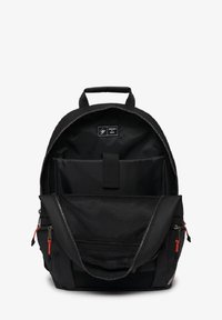 Schwarzer Rucksack aus strapazierfähigem Material mit einem Hauptfach mit Reißverschluss, einer äußeren Netztasche und roten Reißverschlussanhängern.